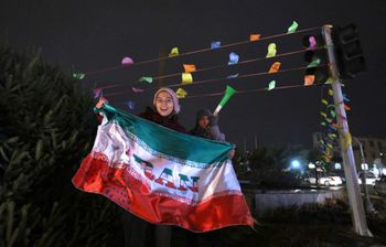 A football fan waves the national flag and celebrates in the capital city of Tehran, Iran, on January 27, 2022, after Iran qualifies for the 2022 World Cup finals in Qatar.