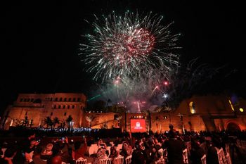 ينظر الناس إلى الألعاب النارية وهي تضيء السماء فوق القلعة الحمراء التاريخية (القلعة الحمراء) خلال حفل إعادة افتتاح المتحف الوطني في العاصمة الليبية طرابلس في 12 ديسمبر 2025.