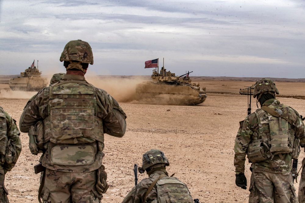 US soldiers watch as a US Bradley Fighting Vehicle drives in the countryside of Deir Ezzor in northeastern Syria on December 7, 2021.
