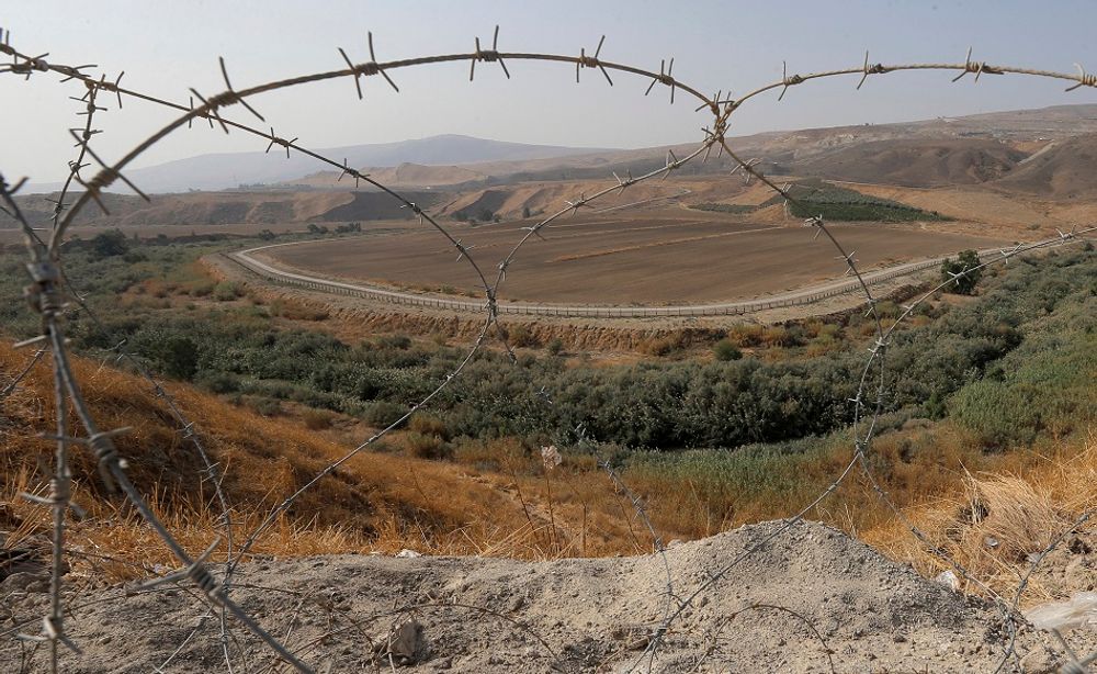 جزء من الحدود الإسرائيلية الأردنية يتم مشاهدتها من خلال سياج من الأسلاك الشائكة من الباقورة، في وادي الأردن.