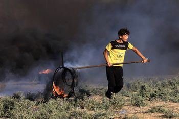 Un jeune Palestinien brûle des pneus près de la barrière frontalière entre Israël et Gaza lors d'un rassemblement anti-israélien à l'est de la ville de Gaza