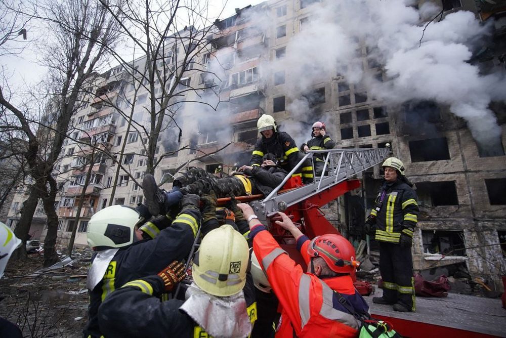 Des pompiers évacuent un homme d'un immeuble incendié après des frappes russes à Kiev, le 14 mars 2022