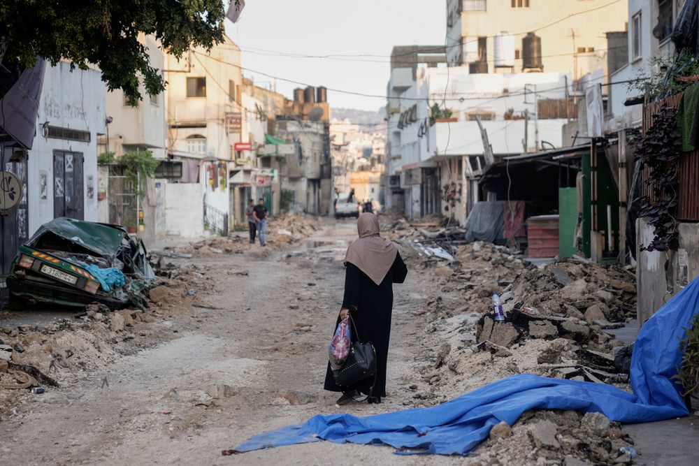 A Palestinian woman walks on a damaged road in the Jenin refugee camp in the West Bank.