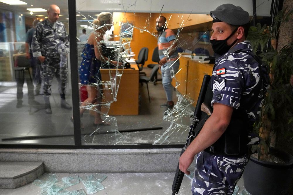 Un policier libanais monte la garde près d'une fenêtre de banque qui a été brisée par des déposants pour sortir de la banque après l'avoir attaquée en essayant d'obtenir de l'argent bloqué, à Beyrouth, au Liban, le 14 septembre 2022.