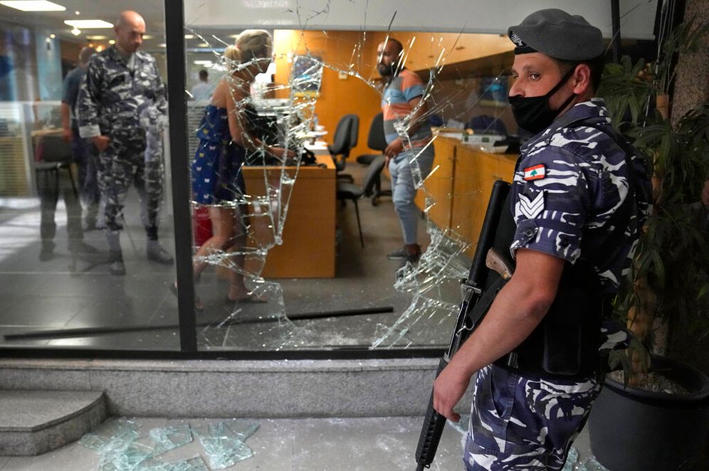AP Photo/Hussein Malla, File Un policier libanais monte la garde près d'une fenêtre de banque qui a été brisée par des déposants pour sortir de la banque après l'avoir attaquée en essayant d'obtenir de l'argent bloqué, à Beyrouth, au Liban, le 14 septembre 2022.