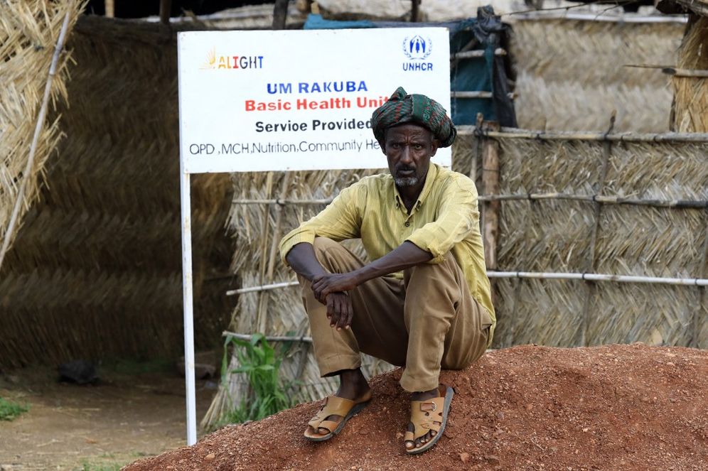 An Ethiopian refugee who fled fighting in the Tigray region sits in front of a United Nations High Commissioner for Refugees (UNHCR) sign at Umm Rakuba camp in eastern Sudan, on August 11, 2021.