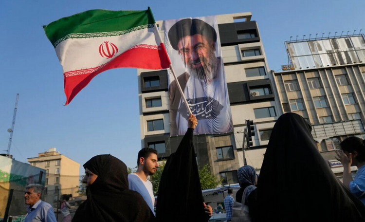 Une femme brandit un drapeau iranien devant une bannière représentant le guide suprême, l’ayatollah Mojtaba Khamenei, lors d’une fête de rue célébrant l’Aïd al-Ghadir, une fête musulmane chiite, à Téhéran (Iran), le 4 juin 2026.
