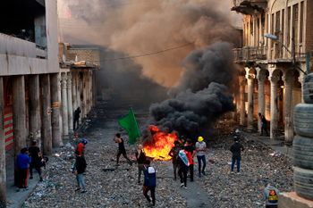 Anti-government protesters set fire while security forces close Rasheed Street during clashes in Baghdad, Iraq, Thursday, Nov. 28, 2019