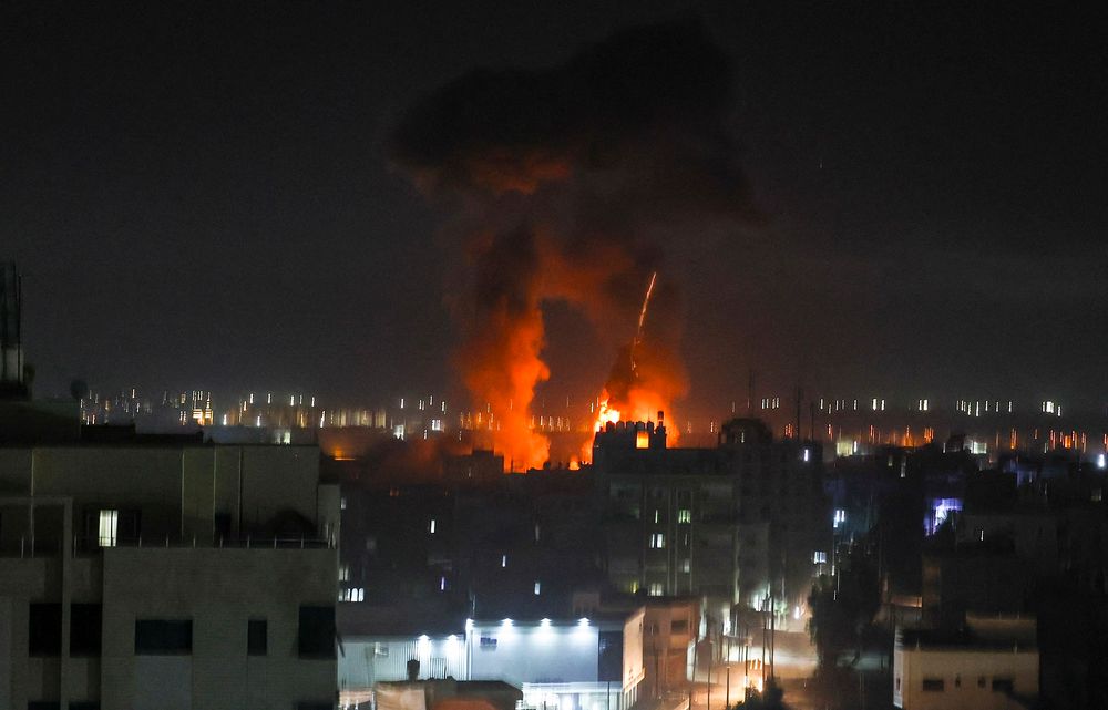 Explosions light-up the night sky above buildings in Gaza City as Israeli forces shell the Palestinian enclave, early on June 16, 2021.