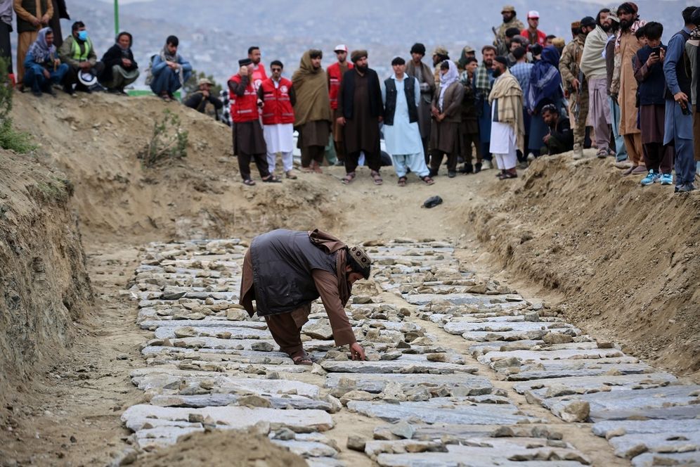 AP Photo/Siddiqullah Alizai رجل يضع الحجارة على القبور خلال جنازة جماعية ثانية لضحايا غارة جوية سابقة استهدفت مركزاً لإعادة تأهيل مدمني المخدرات، في كابول، أفغانستان، الخميس 26 مارس 2026.