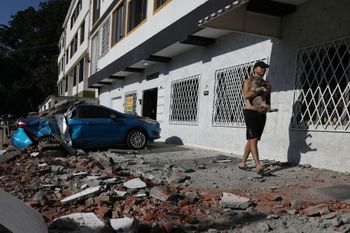A man carries his dog after an earthquake struck Cali, Colombia, Monday, Aug. 10, 2026