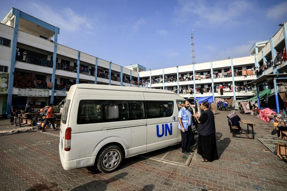A man speaks with a UNRWA worker outside a shelter for displaced Palestinians in Khan Yunis in the southern Gaza Strip.