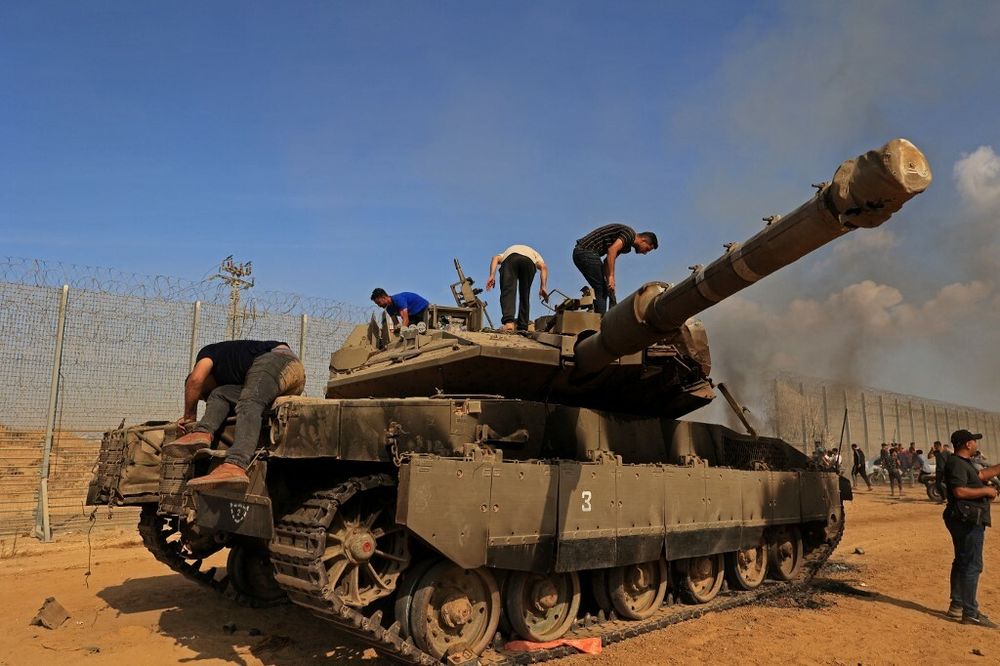 Palestinians take control of an Israeli Merkava battle tank after crossing the border fence with Israel from Khan Yunis in the southern Gaza Strip on October 7, 2023.