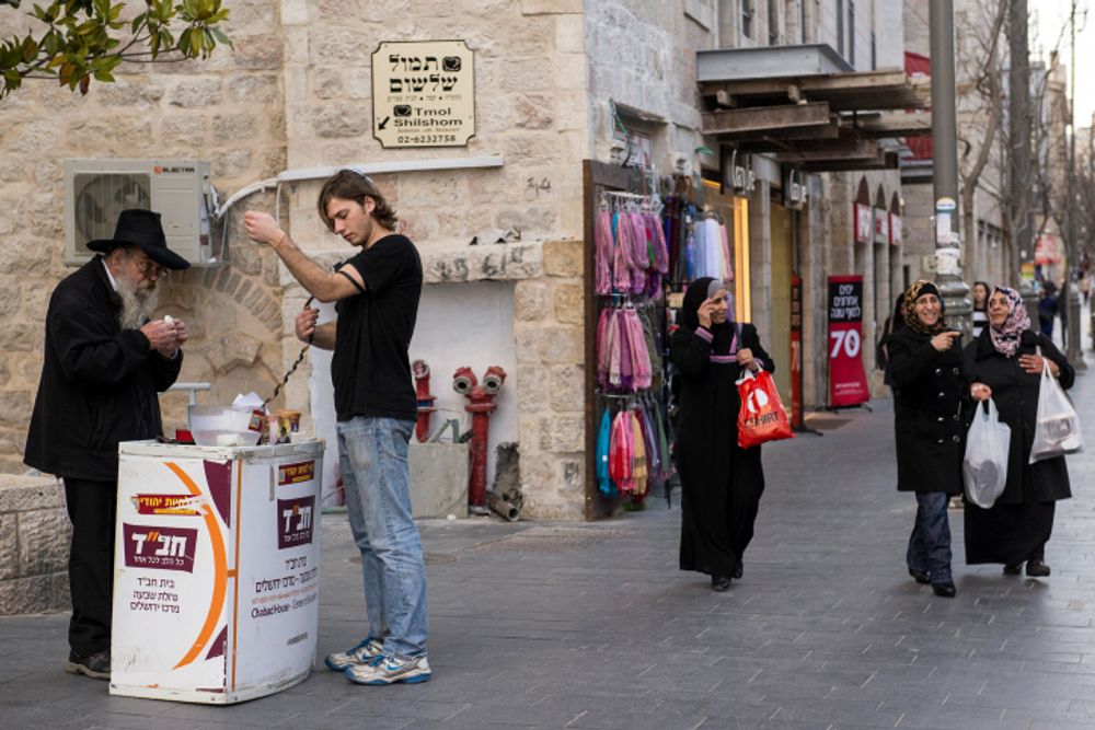 Um judeu deposita tefilin antes de rezar, em uma barraca de Chabad no centro de Jerusalém, Israel.