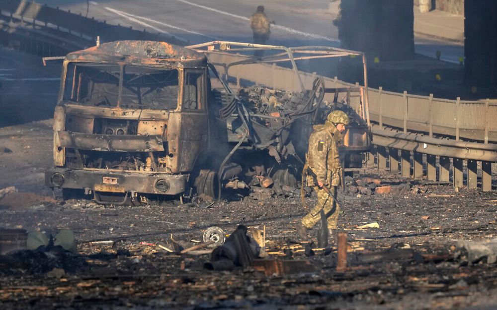 Un soldat ukrainien passe devant les débris d'un camion militaire en feu, dans une rue de Kiev, en Ukraine, le 26 février 2022.