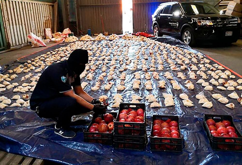 A Saudi custom officer opens imported pomegranates in a foiled attempt to smuggle over five million pills of Captagon from Lebanon, at Jiddah Islamic Port, Saudi Arabia, April 23, 2021.