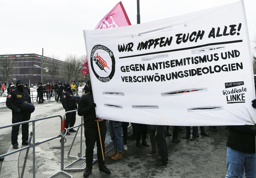 Une banderole indique "Nous vous vaccinons tous contre l'antisémitisme et les théories du complot" lors d'une manifestation sur le thème "Pas de scène pour les idéologues du complot", sur la Heldenplatz à Vienne le 16 janvier 2021