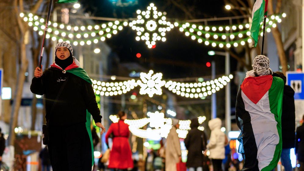 Hamas supporters wear and wave Palestinian flags along Vienna’s famous Mariahilfer shopping street, decorated with Christmas lights on December 21, 2023.