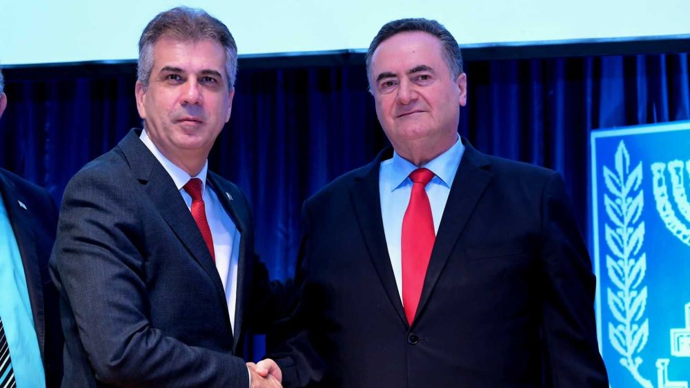Outgoing Israeli Foreign Minister Eli Cohen (L) shakes hands with his successor Minister Israel Katz, as part of a scheduled rotation of portfolios.
