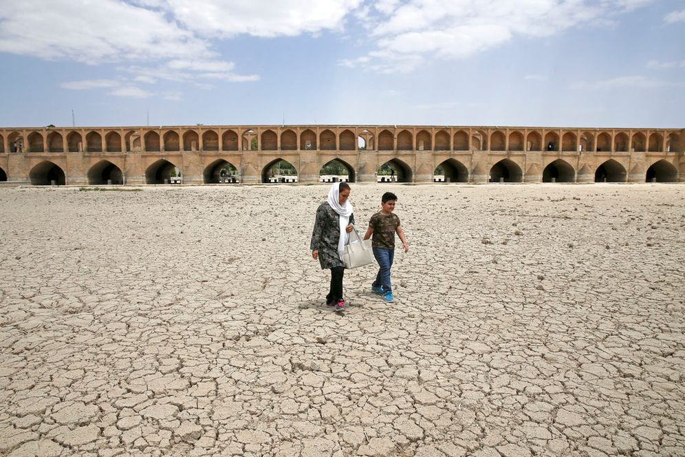 A woman and a boy walk on the dried-up riverbed of the Zayandeh Roud river that no longer runs under the 400-year-old Si-o-seh Pol bridge in Isfahan, Iran, on July 10, 2018.