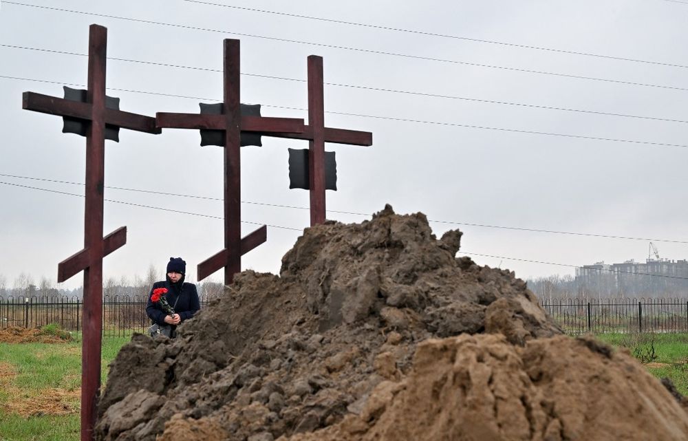 Une personne en deuil assiste aux funérailles d'une famille de trois personnes à Bucha, à la périphérie de Kyiv, en Ukraine, le 22 avril 2022