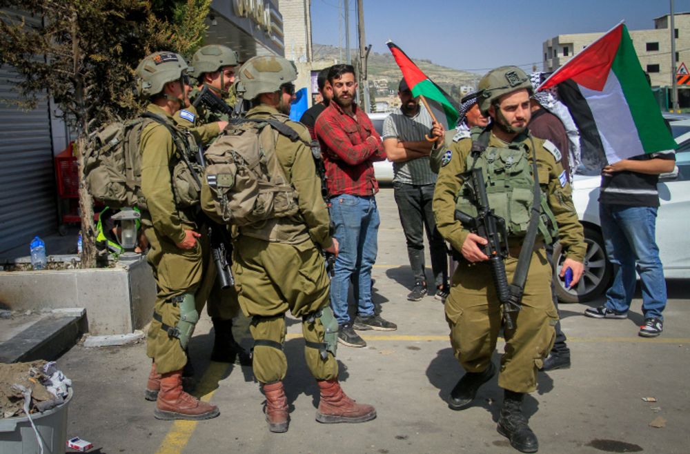 Palestinians confront Israeli soldiers while waving Palestinian flags in the town of Huwara, West Bank.