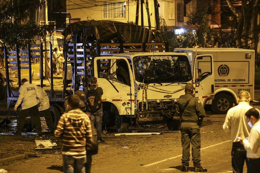 Security personnel inspect a national police truck destroyed by an explosive device in Cali, Colombia, on January 8, 2022.