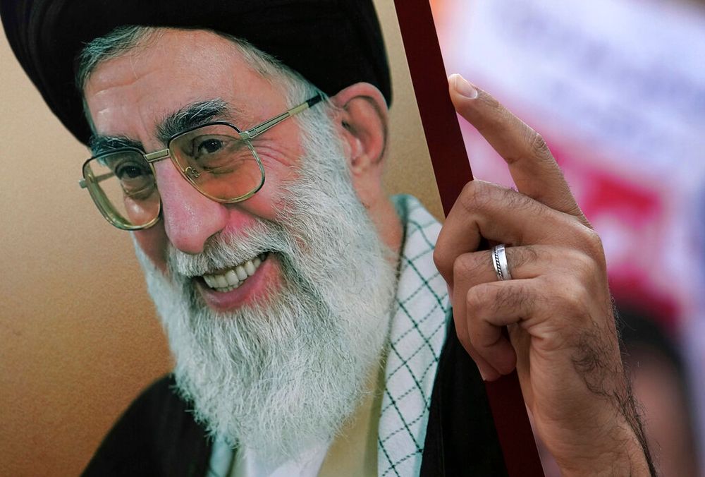 A man holds up a poster of Iranian Supreme Leader Ayatollah Ali Khamenei in Tehran, Iran.