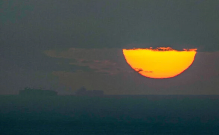 Des navires naviguent dans le golfe Arabo-Persique en direction du détroit d’Ormuz au coucher du soleil, aux Émirats arabes unis, le 23 mars 2026