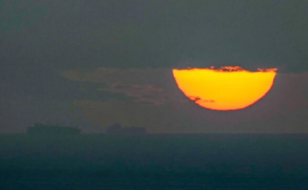 Des navires naviguent dans le golfe Arabo-Persique en direction du détroit d’Ormuz au coucher du soleil, aux Émirats arabes unis, le 23 mars 2026