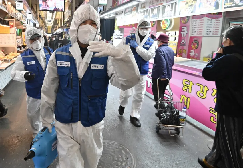 Workers from the Korea Pest Control Association, wearing protective gear, spray disinfectant to help prevent the spread of the COVID-19 novel coronavirus at a market in Seoul on February 24, 2020.