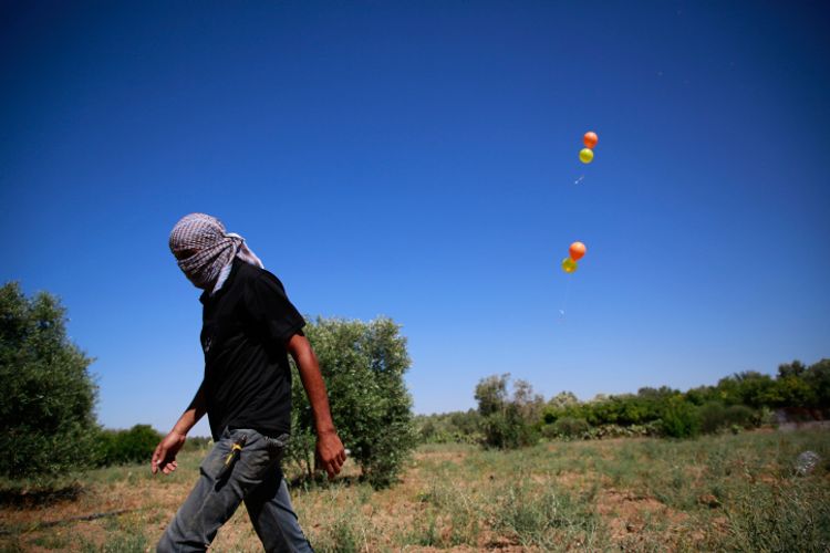 Masked Palestinian supporters of the Islamic jihad movement launch incendiary balloons east of Gaza city, to send across the border fence towards Israel, on June 15, 2021.