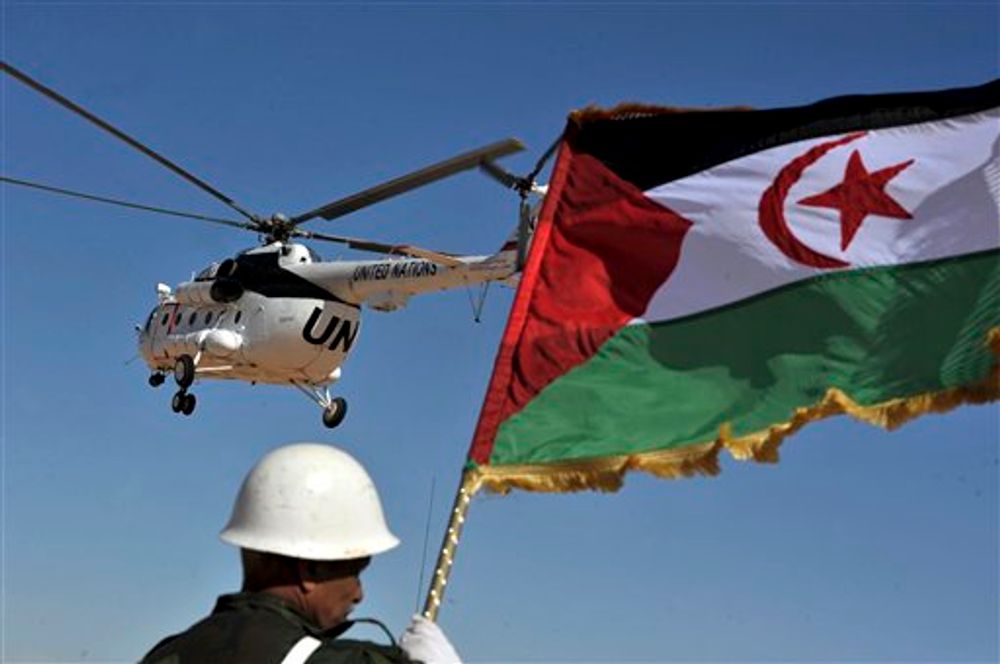 جندي يحمل علم جبهة البوليساريو وفوقه هليكوبتر للأمم المتحدة في مخيم للاجئين بالقرب من تندوف، جنوب غرب الجزائر