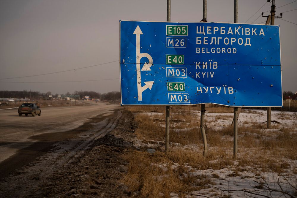 A car drives by bullet and shrapnel riddled road sign on the road to the Russian city of Belgorod.