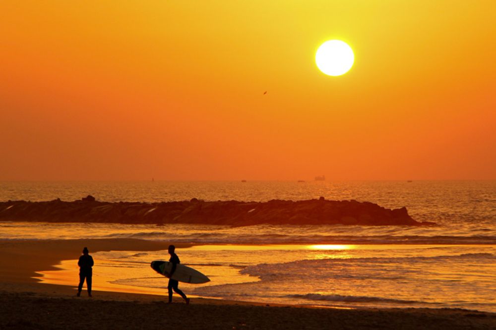 People enjoy the sunset at the beach in Ashkelon, Israel.