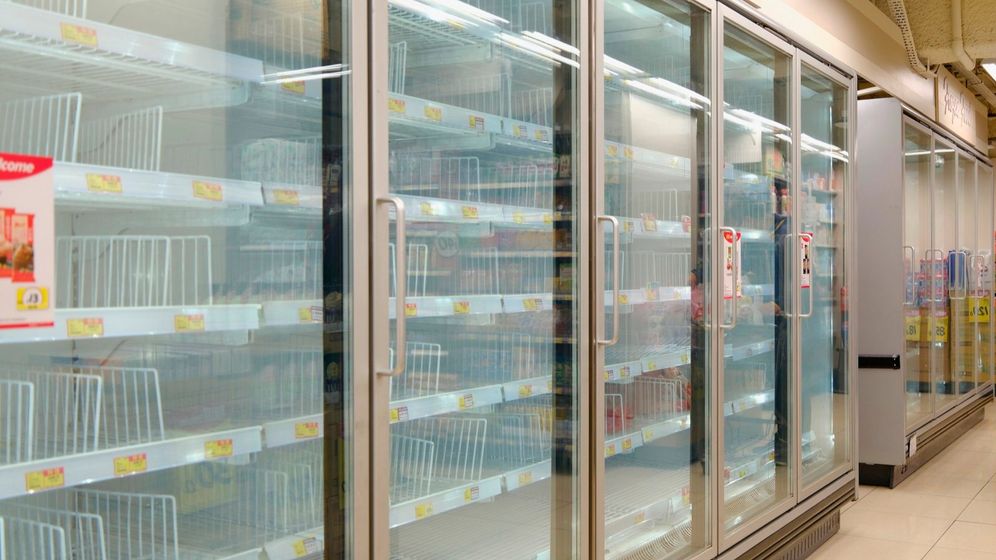 (AP Photo/Vincent Yu) A man wearing a face mask walks past empty shelves of frozen food as residents concerned with possible supply shortages stock up on food at a supermarket in Hong Kong, Tuesday, March 8, 2022. The fast-spreading omicron variant is overwhelming Hong Kong, prompting mass testing, quarantines, supermarket panic-buying and a shortage of hospital beds. Even the morgues are overflowing, forcing authorities to store bodies in refrigerated shipping containers.