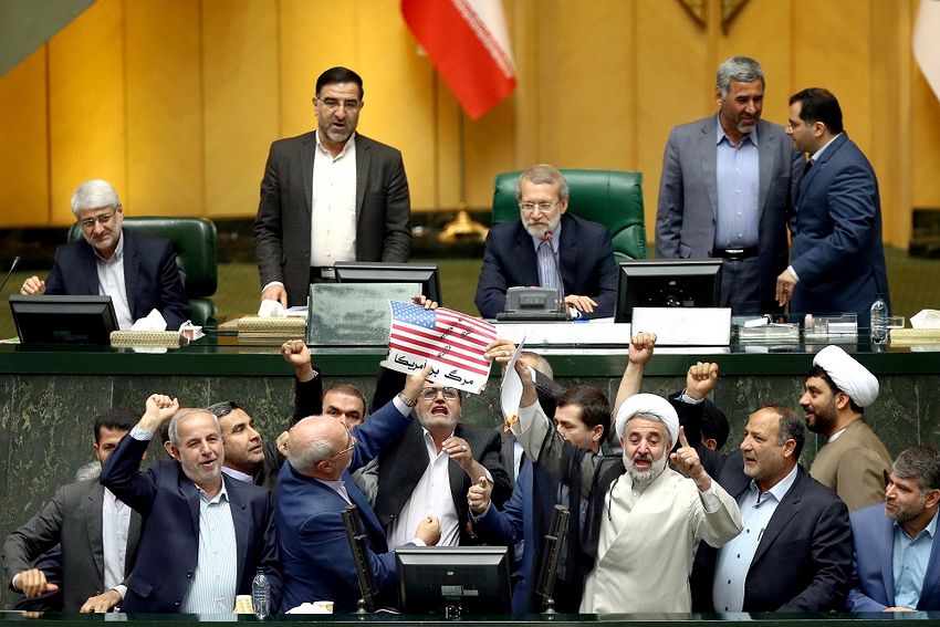 FILE- Iranian lawmakers burn two pieces of papers representing the U.S. flag and the nuclear deal as they chant slogans against the U.S. at the parliament in Tehran, Iran, Wednesday, May 9, 2018.