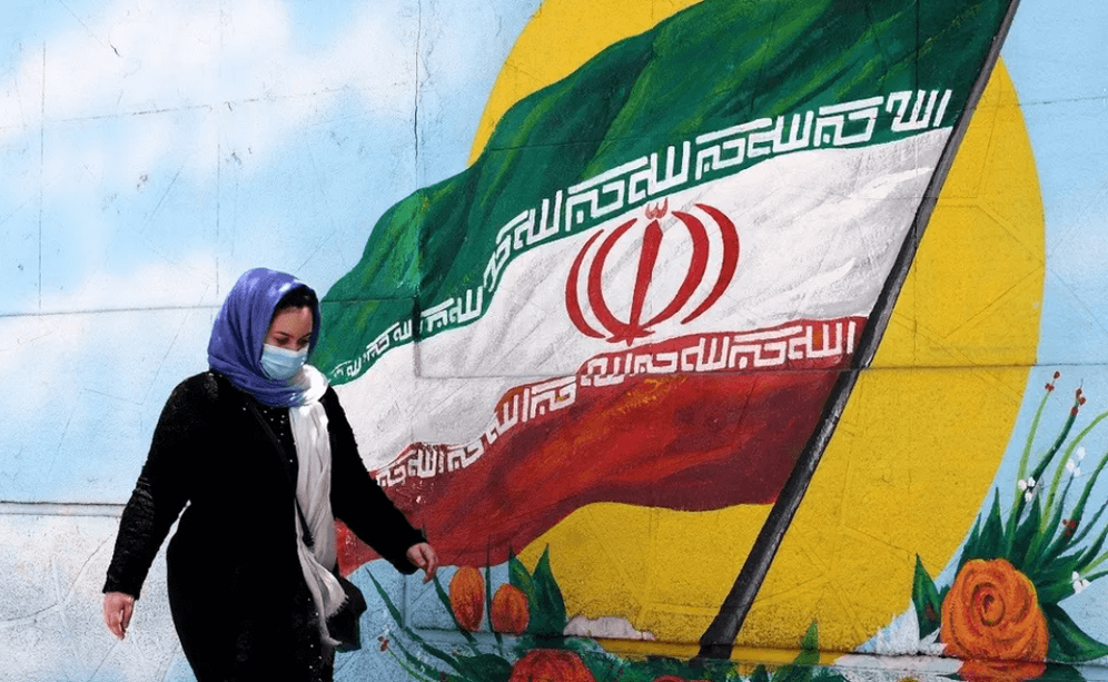 Une femme iranienne passe devant une peinture murale représentant le drapeau national iranien à Téhéran