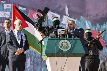 Yahia al-Sinwar (2nd-L), Gaza Strip chief of the Palestinian Islamist Hamas movement, stands by a masked fighter of Hamas' Qassam Brigades while addressing supporters during a rally marking the 35th anniversary of the group's foundation, in Gaza City.
