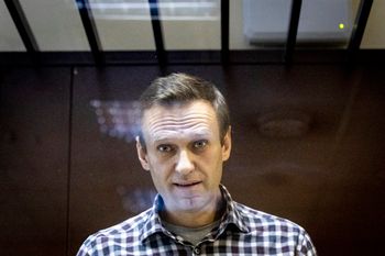 FILE - Russian opposition leader Alexei Navalny looks at photographers standing behind a grass of the cage in the Babuskinsky District Court in Moscow, Russia, on February 20, 2021.