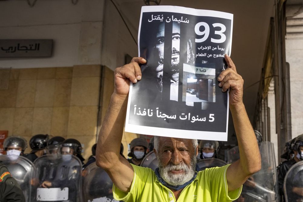 A Moroccan activist holds a banner with the image of jailed Moroccan journalist Soulaimane Raissouni during a protest in Rabat, Morocco, on July 10, 2021.