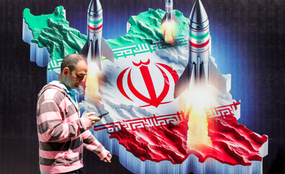 A man passing in front of a mural representing Iranian missiles launched at Israel 