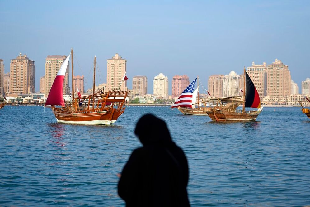 امرأة تلتقط صوراً لقوارب تحمل أشرعة بألوان أعلام بولندا والولايات المتحدة وألمانيا بالقرب من شاطئ كتارا في الدوحة، قطر، الخميس 1 ديسمبر 2022