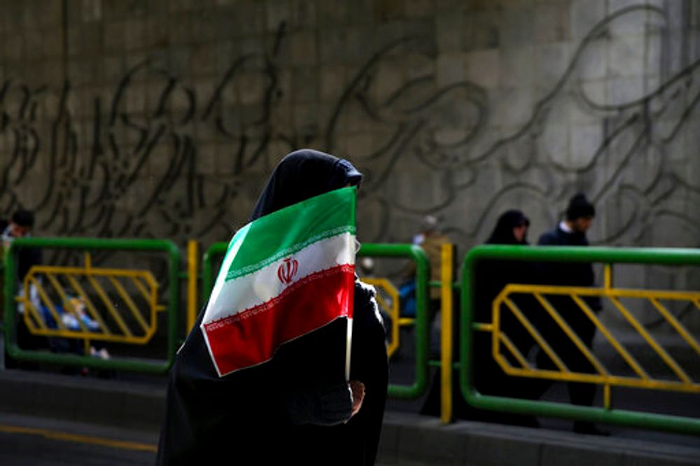 A woman holds Iran's national flag during a rally in Tehran, Iran, on February 11, 2016.