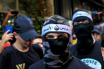 Members of the Lions' Den groups give away sweets to people during celebrations of the Birth of the Prophet Muḥammad in the West Bank city of Nablus