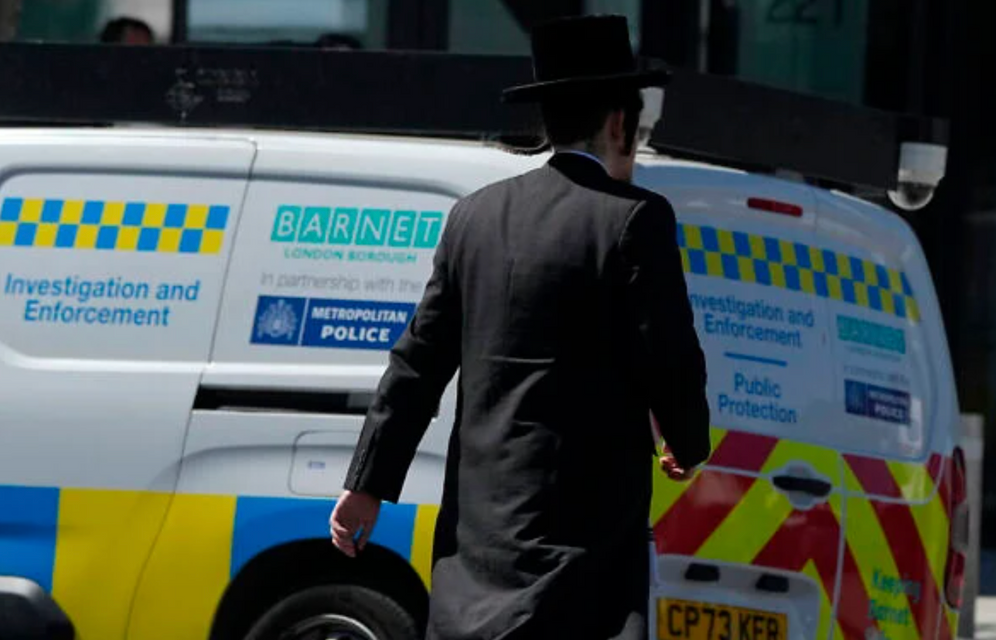 Un homme passe devant un véhicule d’enquête et d’intervention à Londres, le 30 avril 2026, près du lieu où deux Juifs ont été poignardés dans le quartier de Golders Green. 