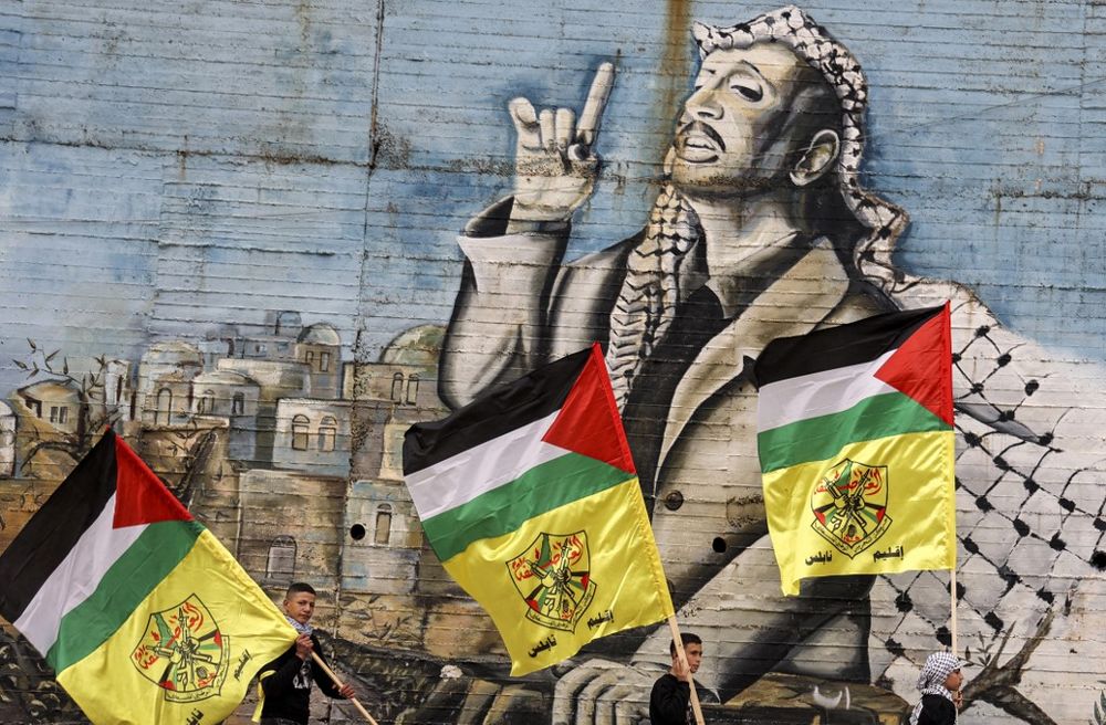 De jeunes membres du Fatah défilent aux abords d'une peinture murale représentant Yasser Arafat, le 4 janvier 2022