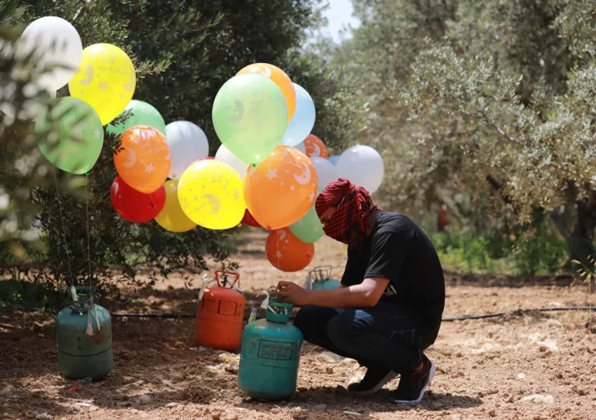 Palestinian youth prepare molotov cocktails attached to balloons, to send to Israeli land east of Bureij refugee camp, in the Gaza Strip, on May 31, 2019.