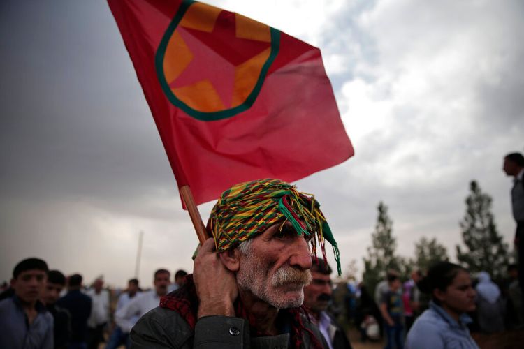 Le Kurde turc Rifat Horoz brandit un drapeau kurde alors qu'il assiste aux funérailles de quatre combattantes kurdes dans un cimetière de Suruc, à la frontière turco-syrienne, le 14 octobre 2014.