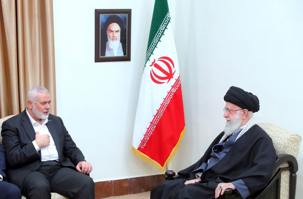 In this photo released by an official website of the office of the Iranian Supreme Leader, Hamas chief Ismail Haniyeh (left) speaks with Supreme Leader Ayatollah Ali Khamenei in a meeting in Tehran, Iran